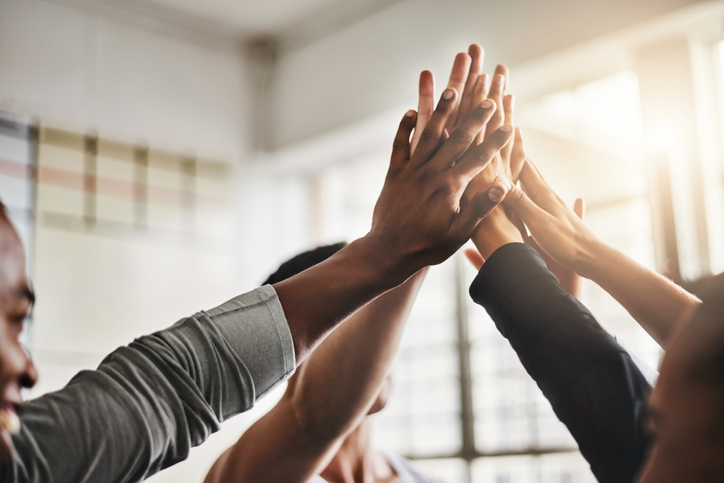 Shot of a group of young people giving each other a high five during their workout in a gym